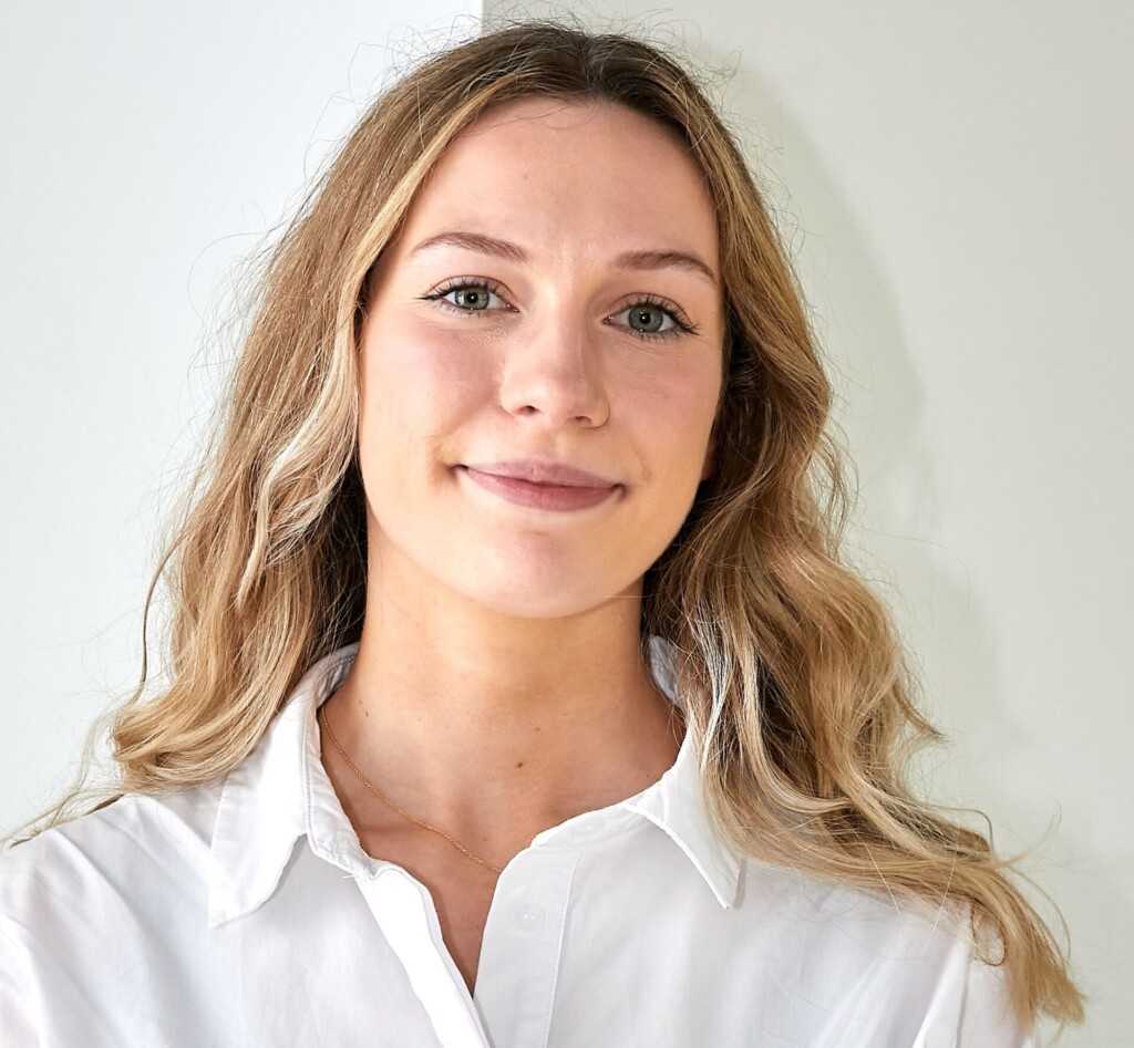 A young woman in a white shirt with long blonde hair.