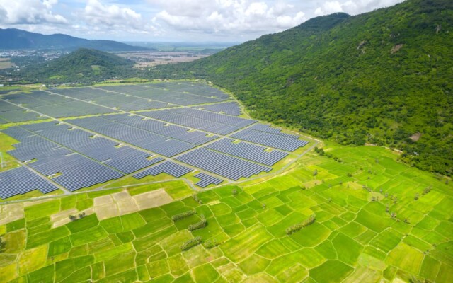 Grey solar panels with green fields and dark green mountains