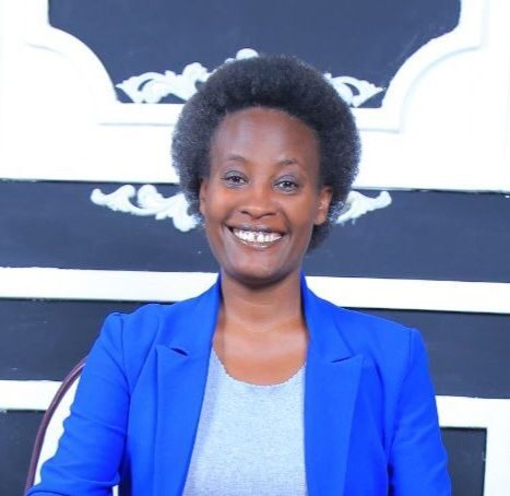 a black woman smiling and dressed in a blue jacket