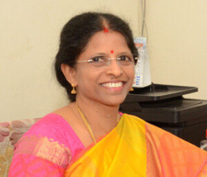 A smiling Indian woman in orange and pink Sari