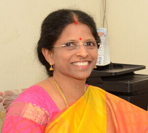 A smiling Indian woman in orange and pink Sari