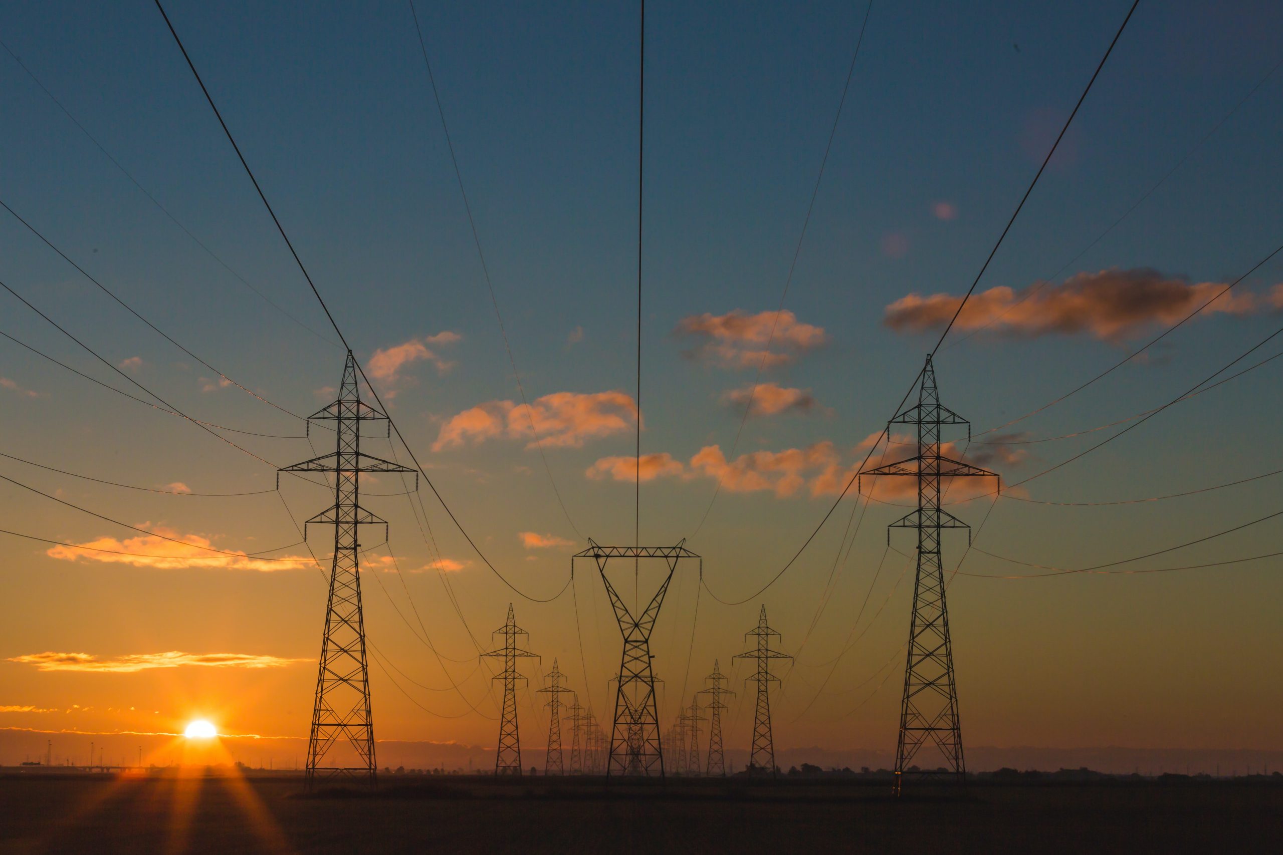 Lines of transmission towers with the sun setting in the background